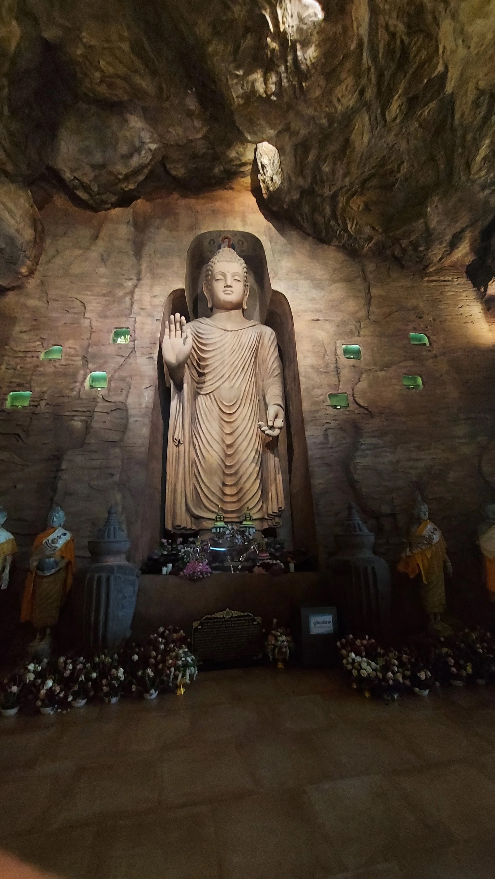 Estátua de Buda em relevo em nicho de rocha esculpida com iluminação suave no interior de uma caverna no Wat Saket, em Banguecoque.