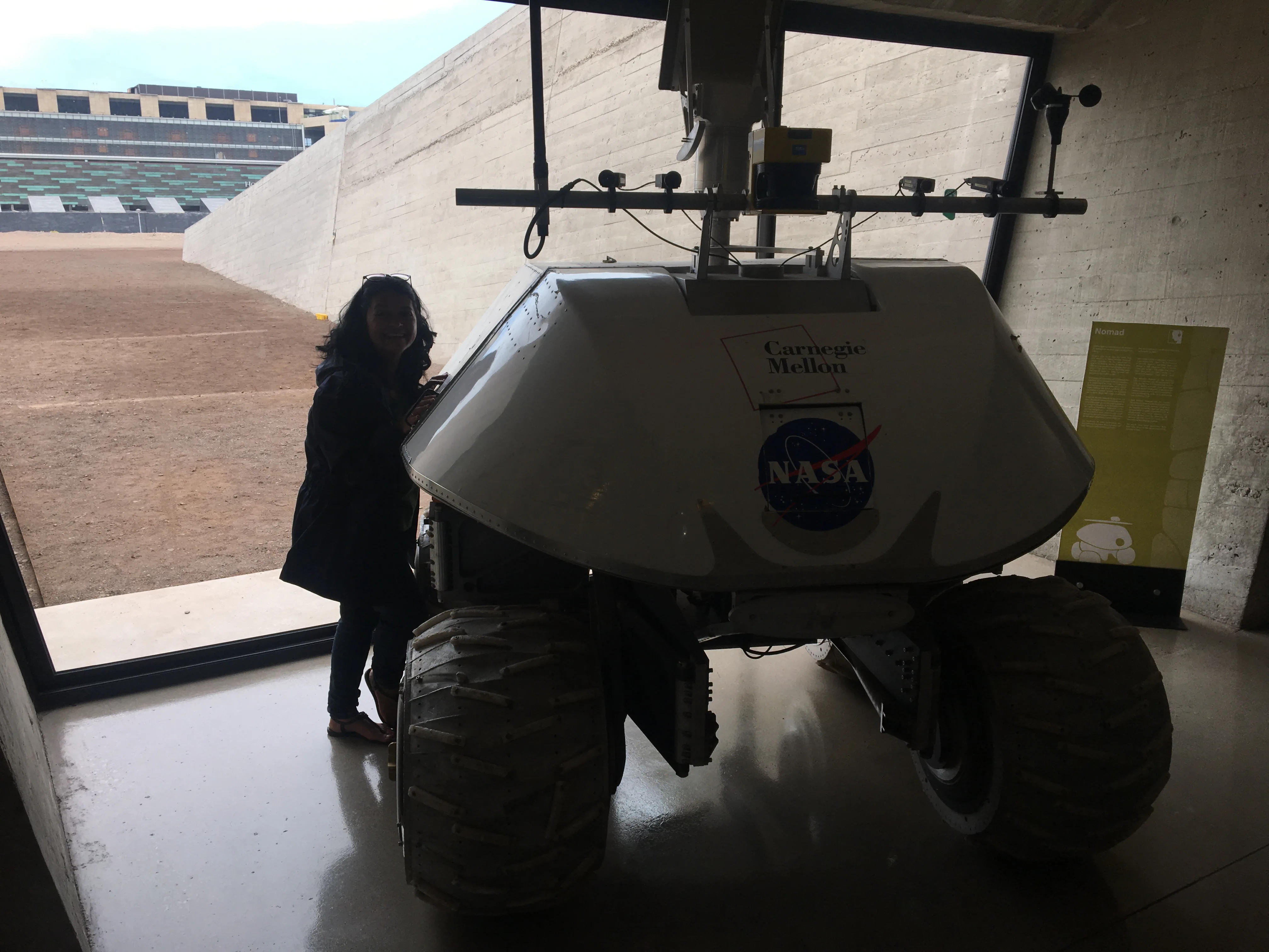 Uma mulher em pé ao lado da réplica do rover espacial da NASA na área de exposição do museu de Antofagasta.