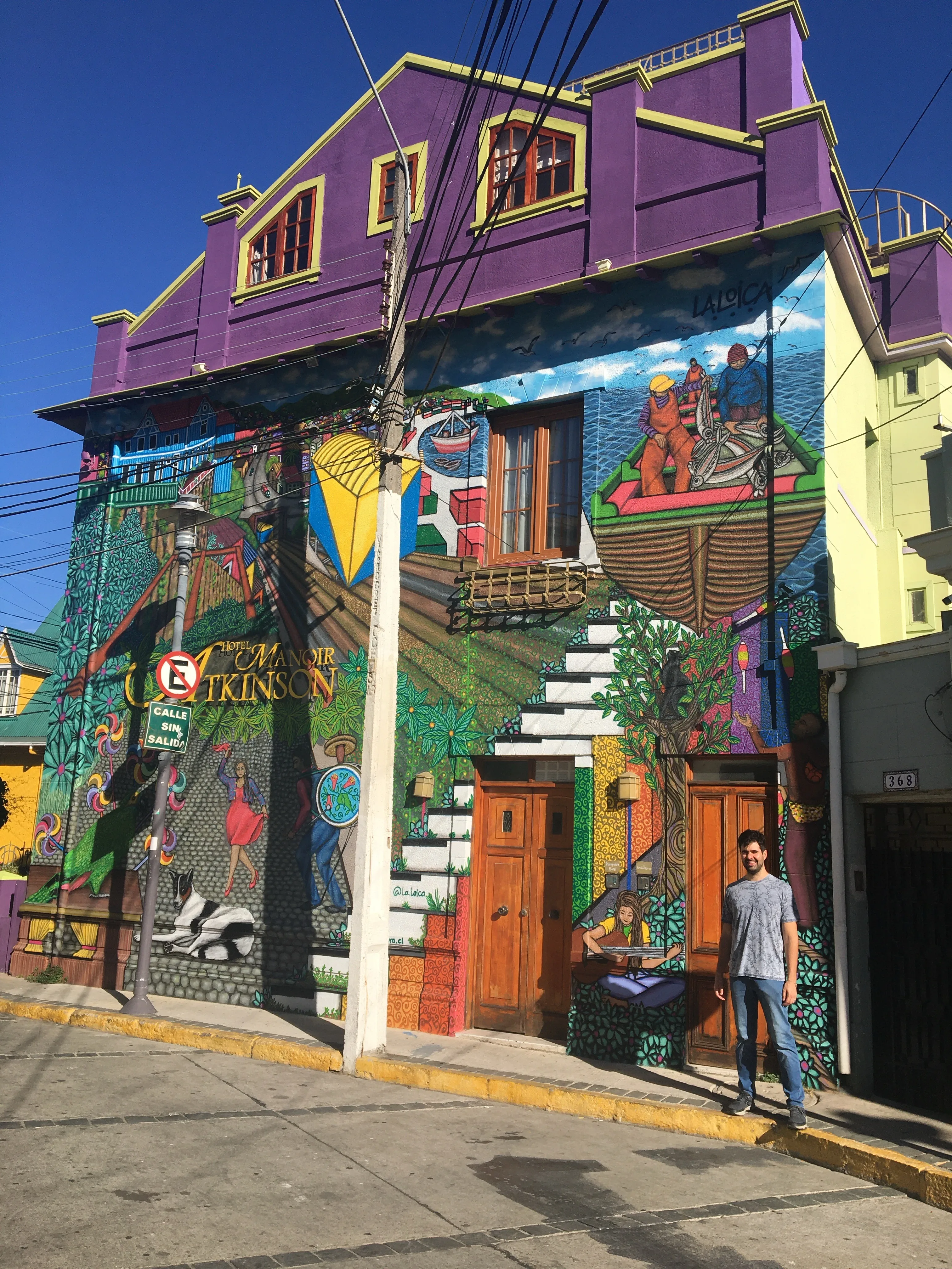 Ladeira íngreme no Cerro Alegre, em Valparaíso, cercada por casarões históricos pintados com cores vibrantes e cobertos por grafites artísticos.