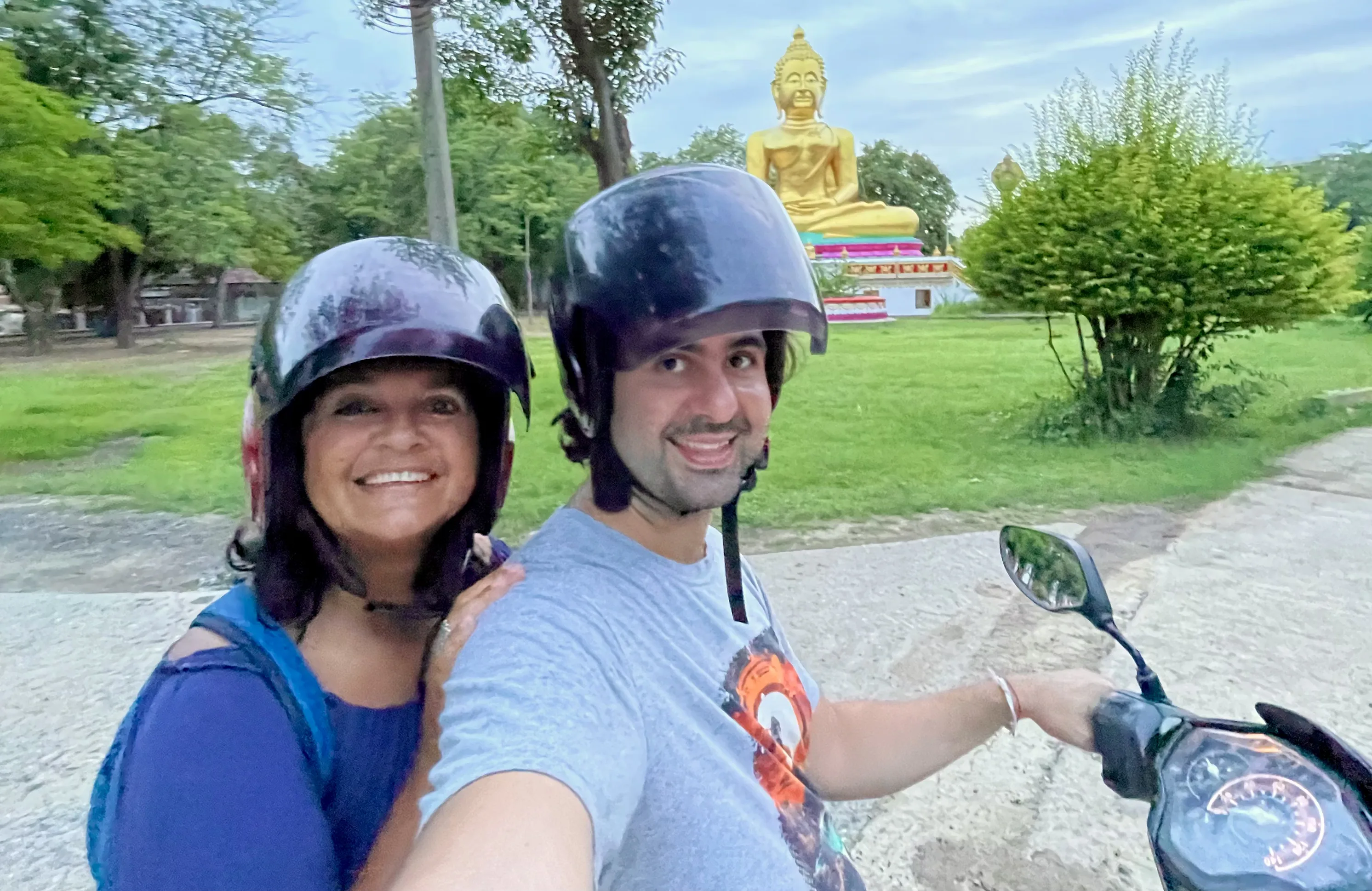 Casal de capacete em selfie na moto rumo ao templo Wat Muang na Tailândia