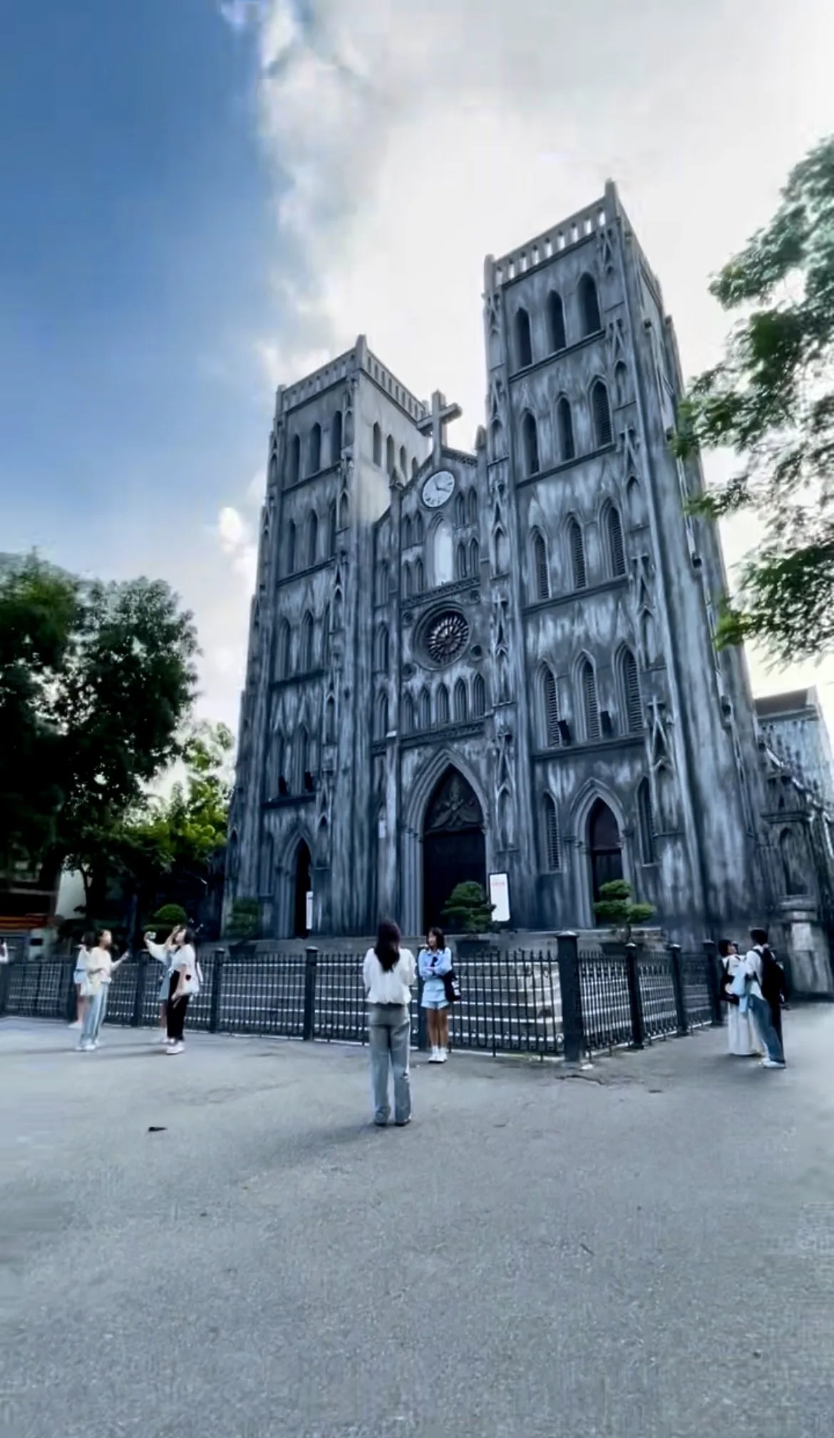 Imponente fachada principal da Catedral de São José, construída em pedra cinzenta escura com marcas de envelhecimento, destacando-se as duas torres gêmeas simétricas, uma grande rosácea central em ogiva, portões de madeira trabalhada e cruzes de pedra no topo.