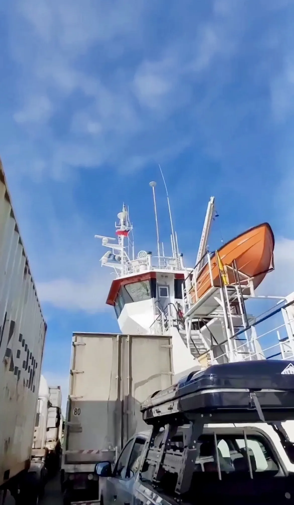 Veículos e caminhões de carga estacionados no convés de um ferry no Estreito de Magalhães, com a cabine de comando ao fundo.