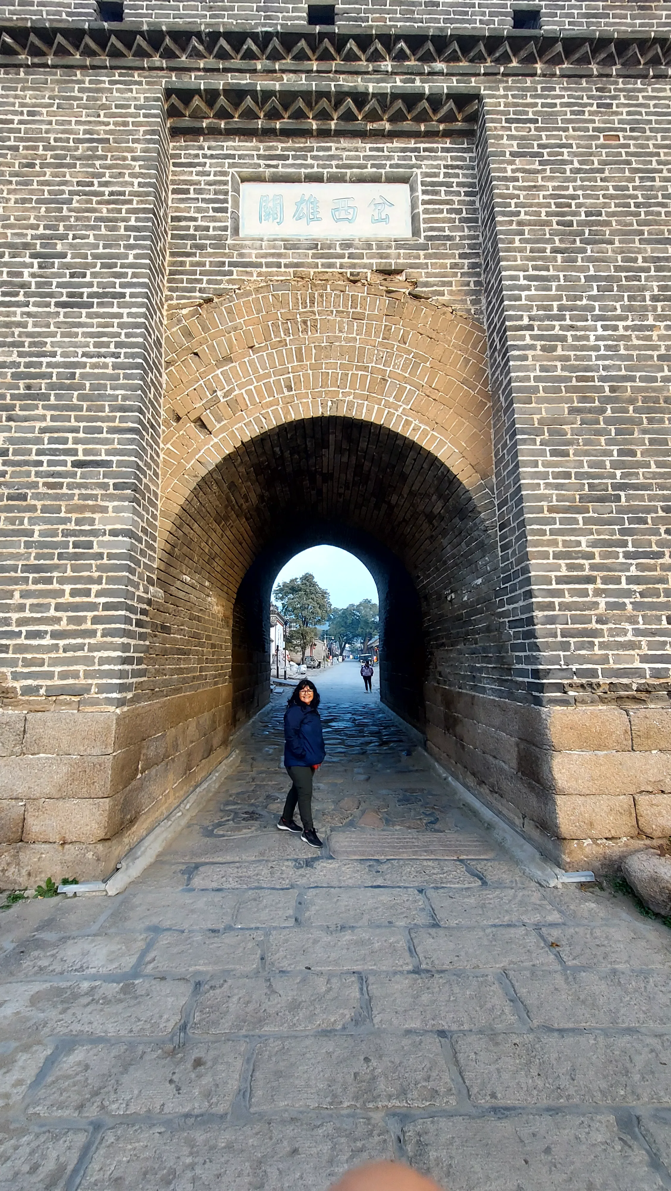 Turista posando sob o imponente portão de tijolos e arco de pedra na entrada de Badaling na Muralha da China