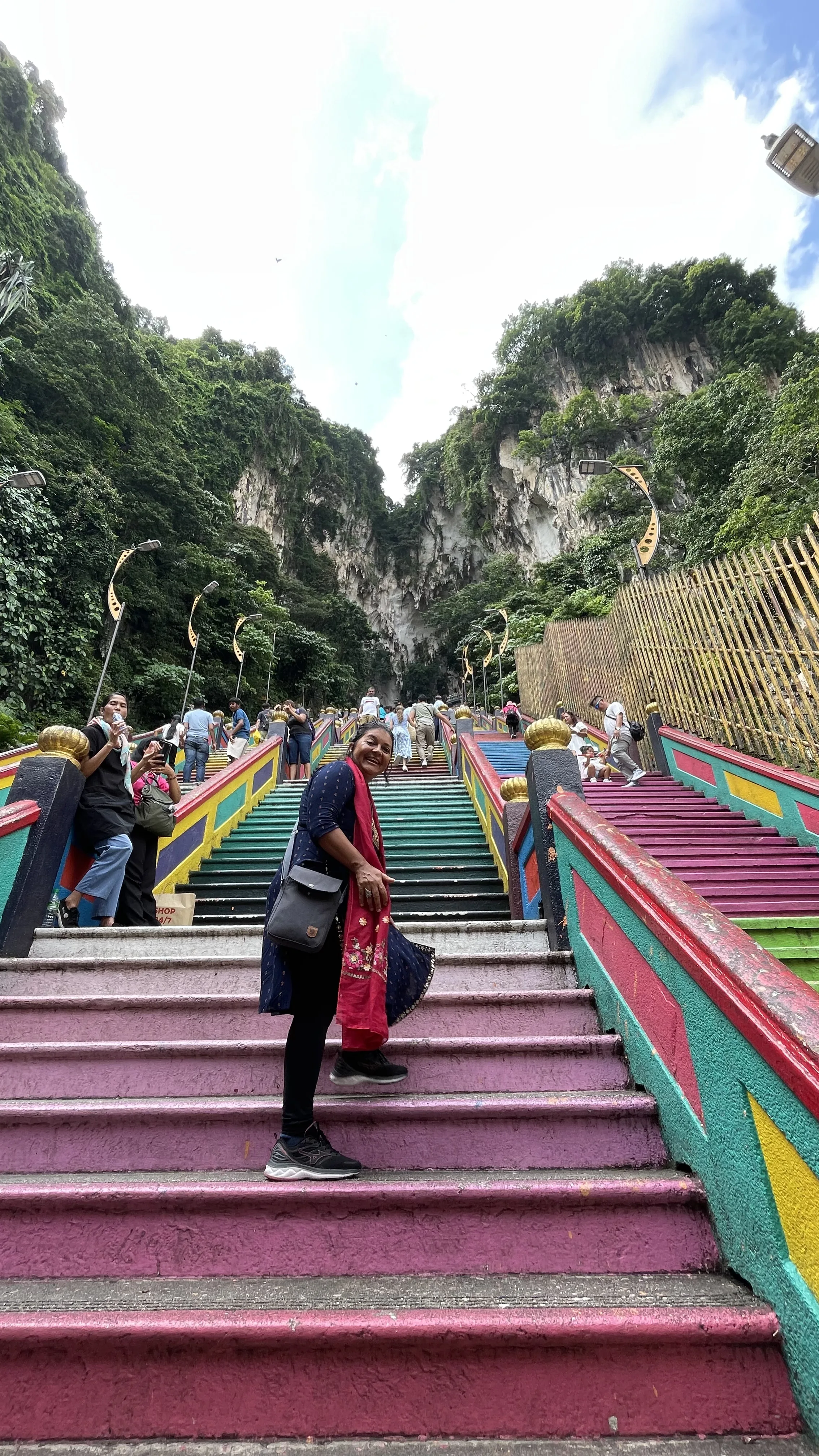 Uma mulher subindo a colorida escadaria monumental em direção às cavernas de Batu Caves, na Malásia.