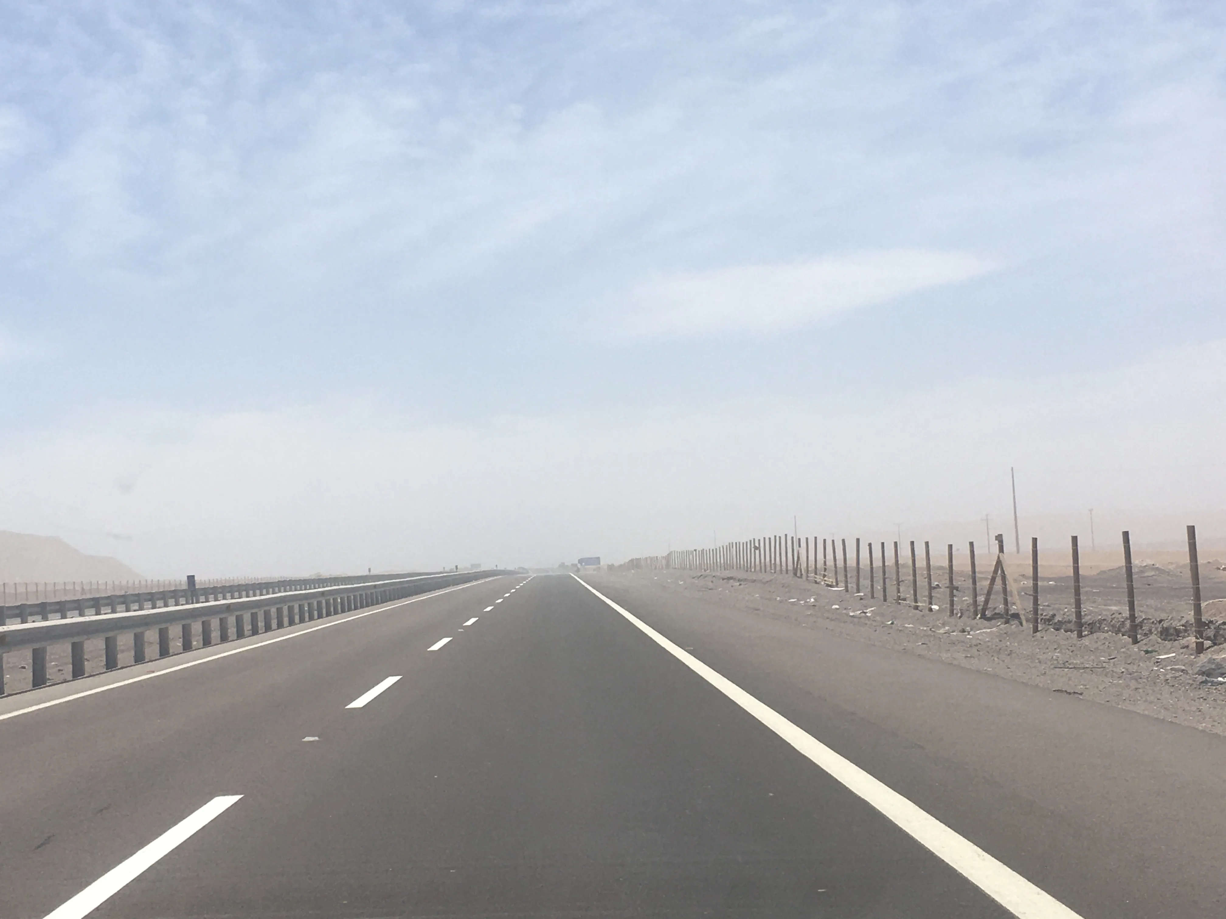 Rodovia asfaltada com faixas brancas cortando a paisagem árida e desértica da Ruta 5 no norte do Chile sob um céu claro.
