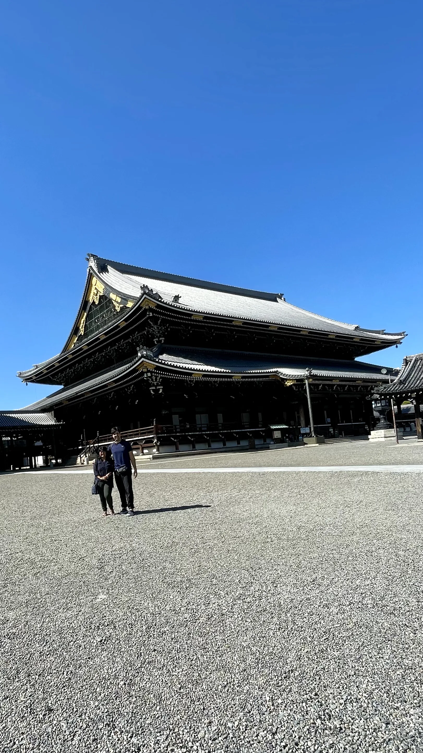 Visitantes no pátio de um templo em Kyoto sob um céu azul