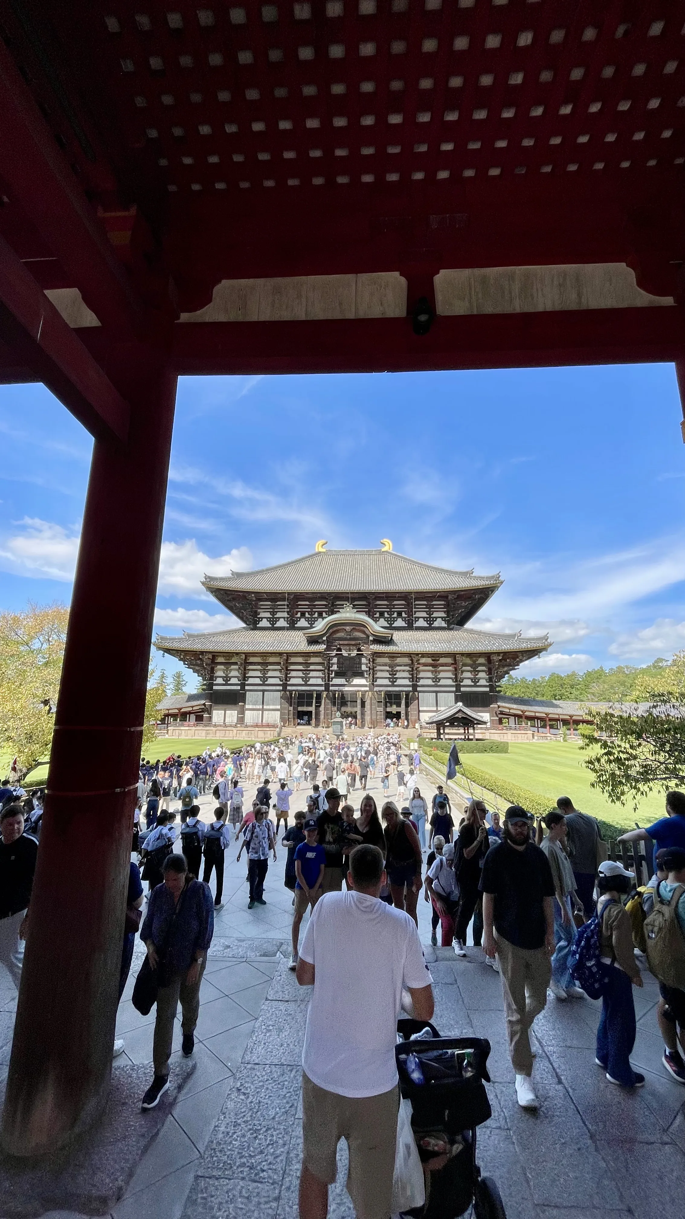 Turistas caminham pelo pátio em direção ao Templo Todai-ji sob o céu azul em Nara no Japão.