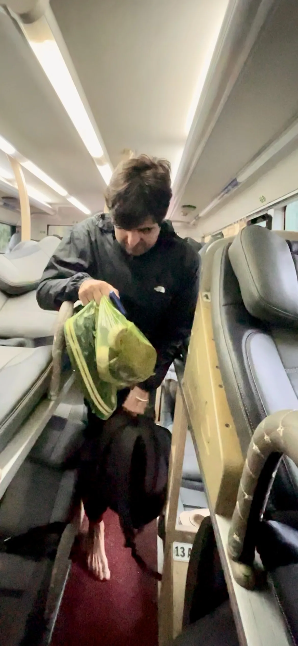 Passageiro a organizar a bagagem no corredor estreito de um autocarro-cama equipado com beliches no Vietname.