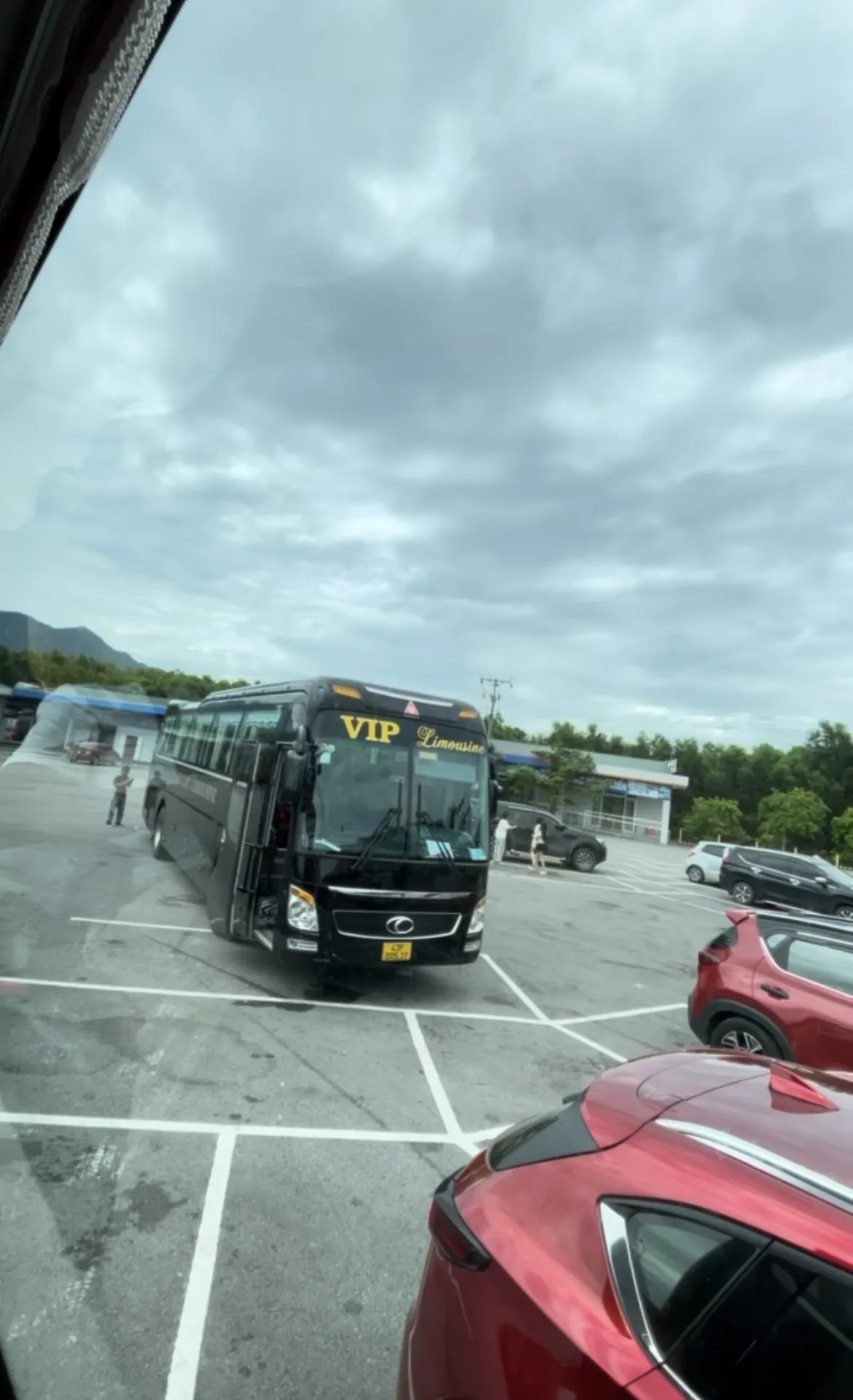 Autocarro VIP Limousine estacionado numa área de descanso espaçosa com outros veículos ao fundo no Vietname