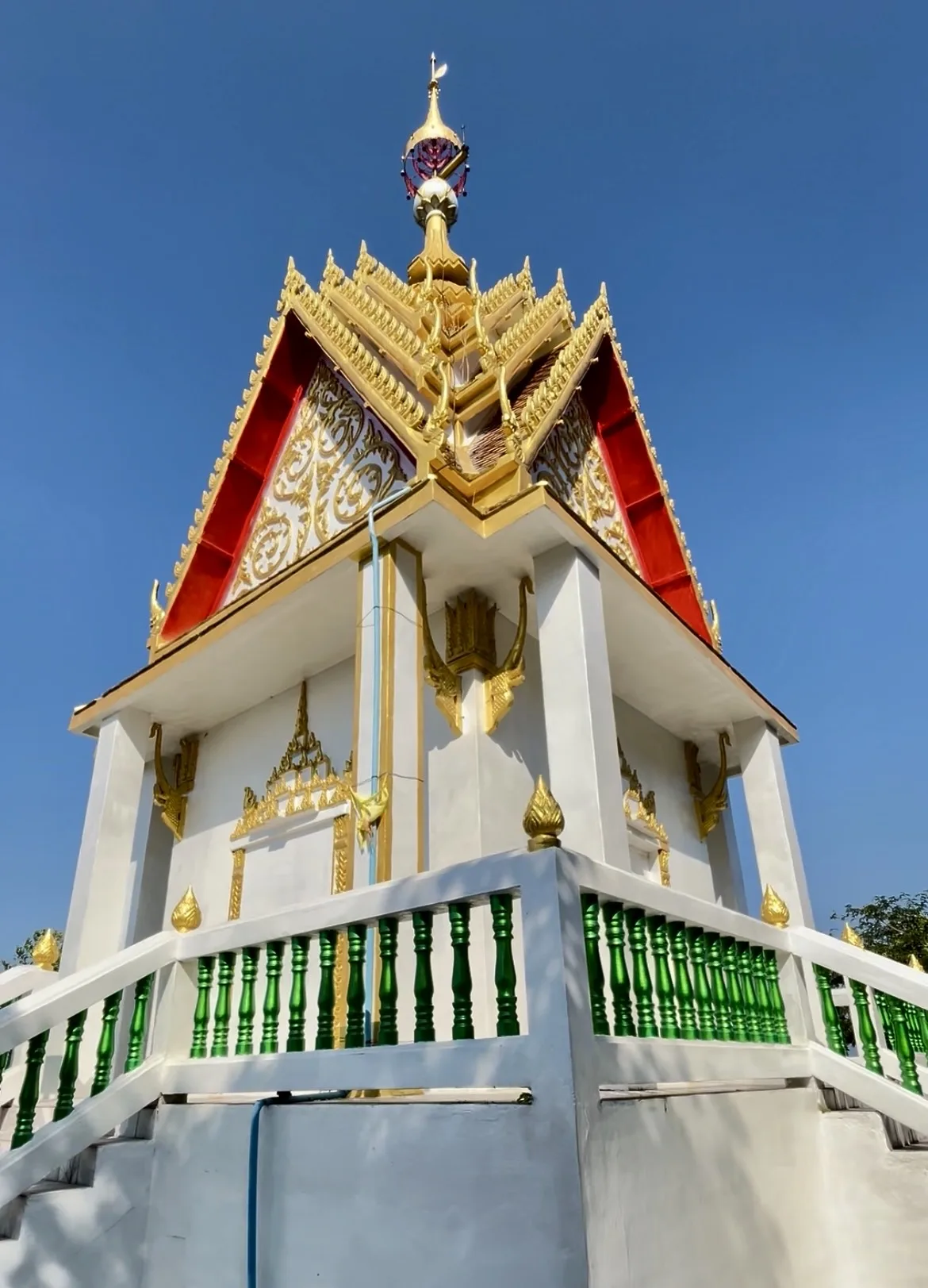 Pequeno templo tailandês com estrutura branca e telhado ornamentado em vermelho e dourado em Ko Lan.