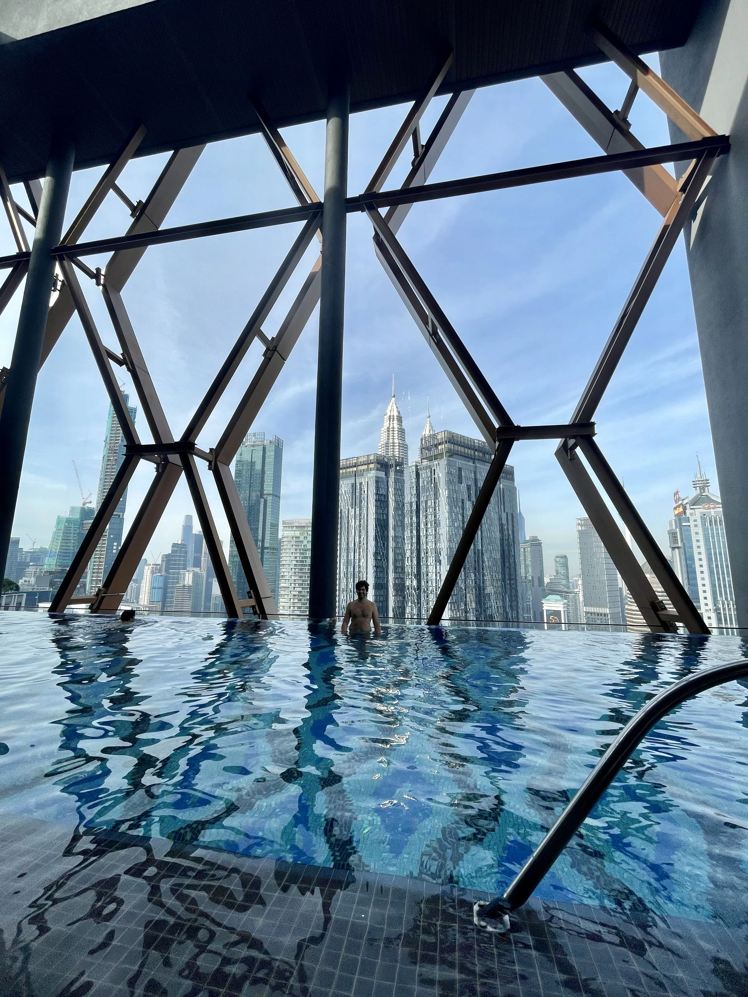 Piscina de borda infinita com vista panorâmica para o horizonte e as Torres Petronas em Kuala Lumpur.
