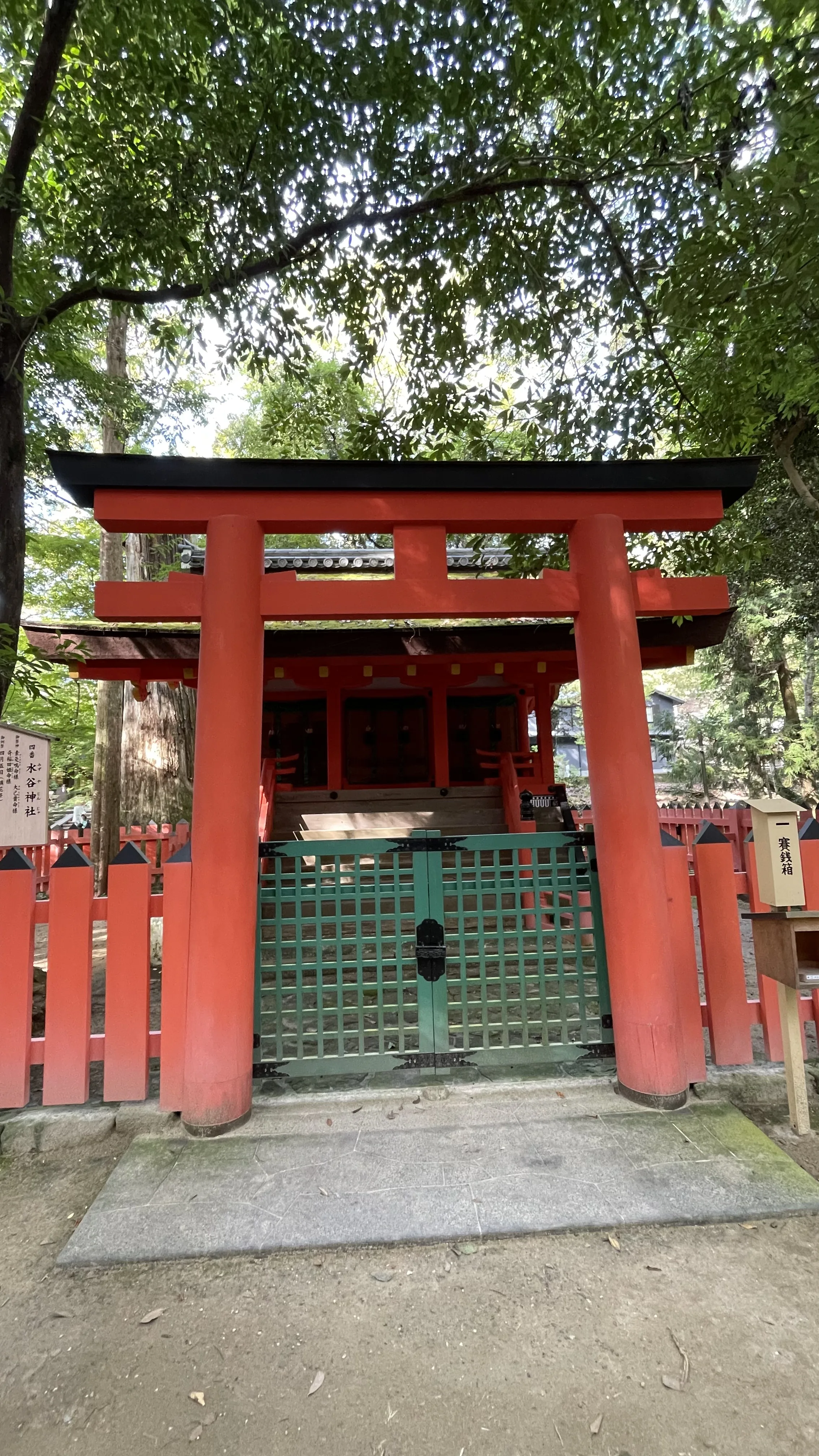 Torii vermelho de madeira com portão verde protege o pavilhão do Santuário Mizutani no complexo xintoísta de Nara, no Japão.