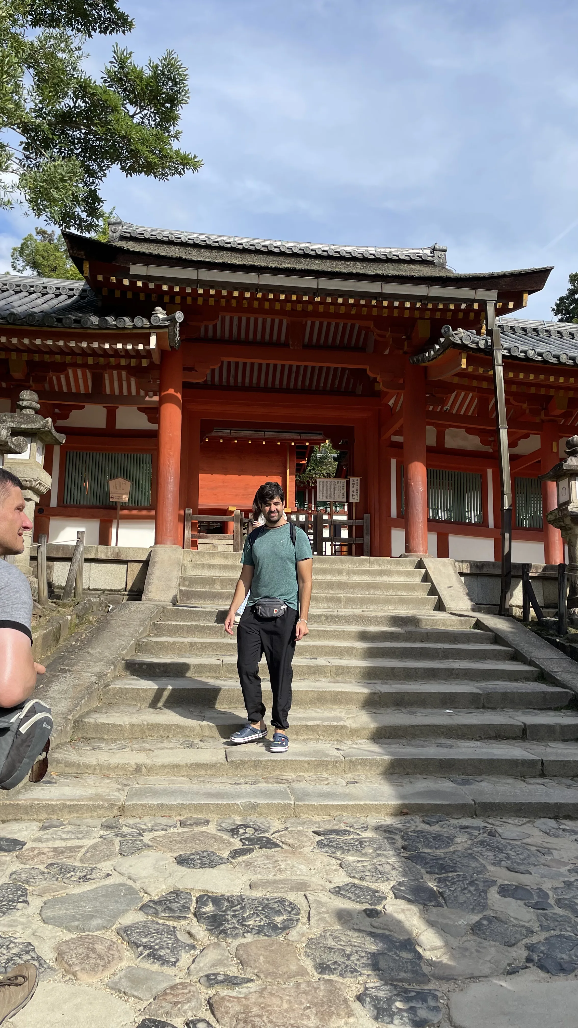 Turista desce escadaria de pedra do portão vermelho Minamimon no Santuário Kasuga Taisha, famoso ponto turístico em Nara, Japão.