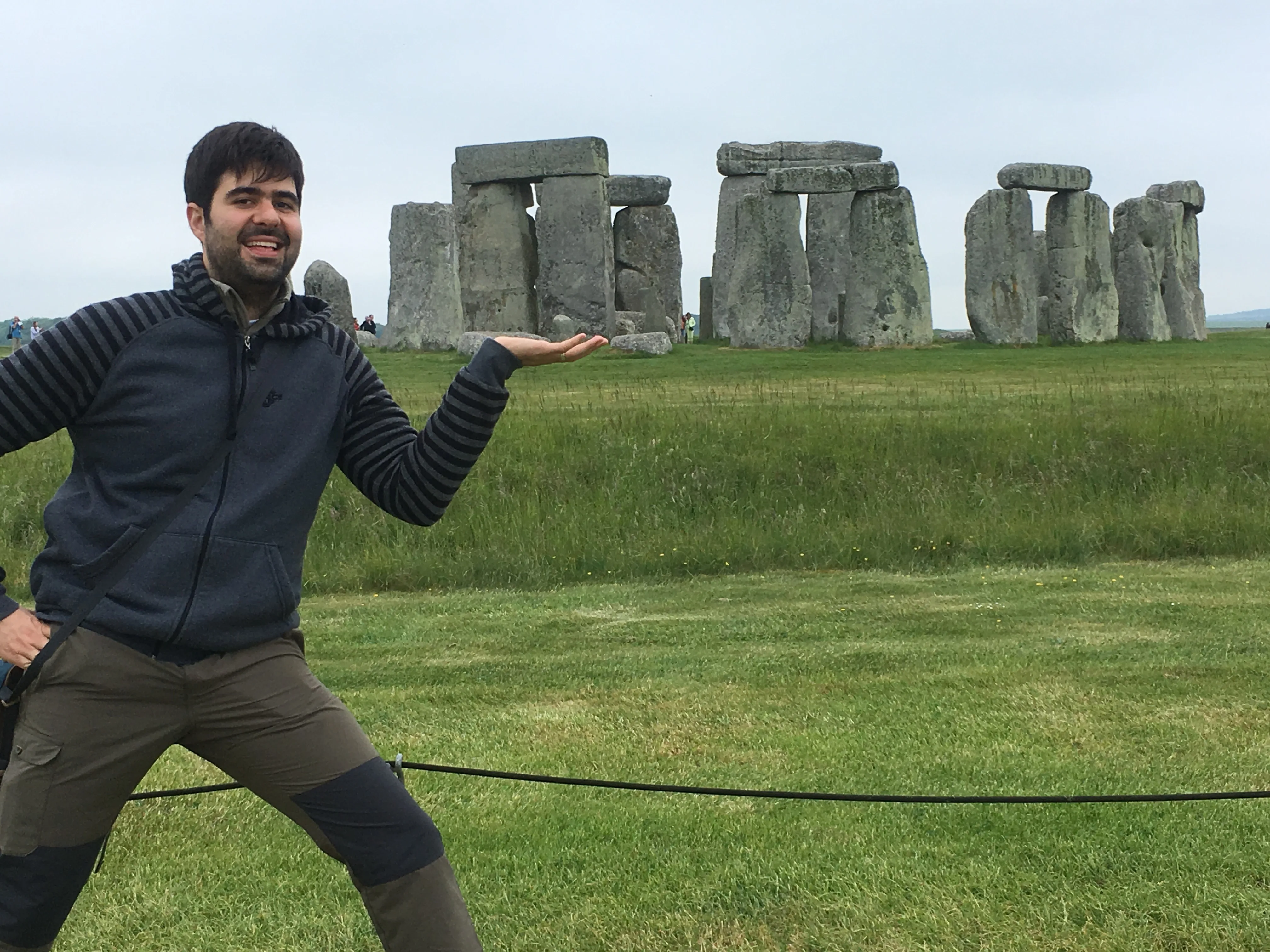 Rosto de viajante em primeiro plano ao lado da pedra isolada Heel Stone no gramado de Stonehenge na Inglaterra.