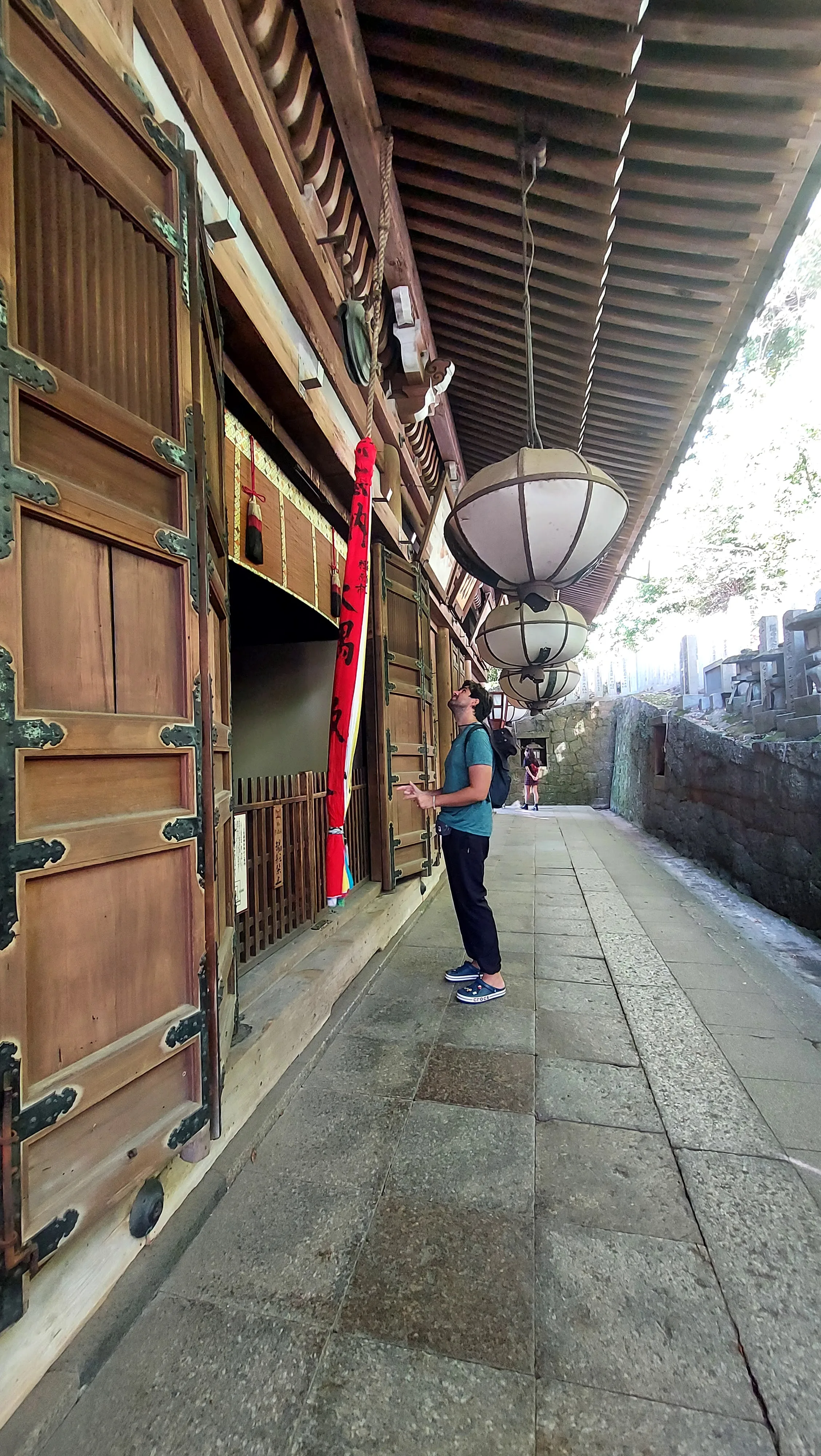 Turista observa as grandes lanternas suspensas e portas de madeira do pavilhão Nigatsu-do no Templo Todaiji em Nara, Japão.