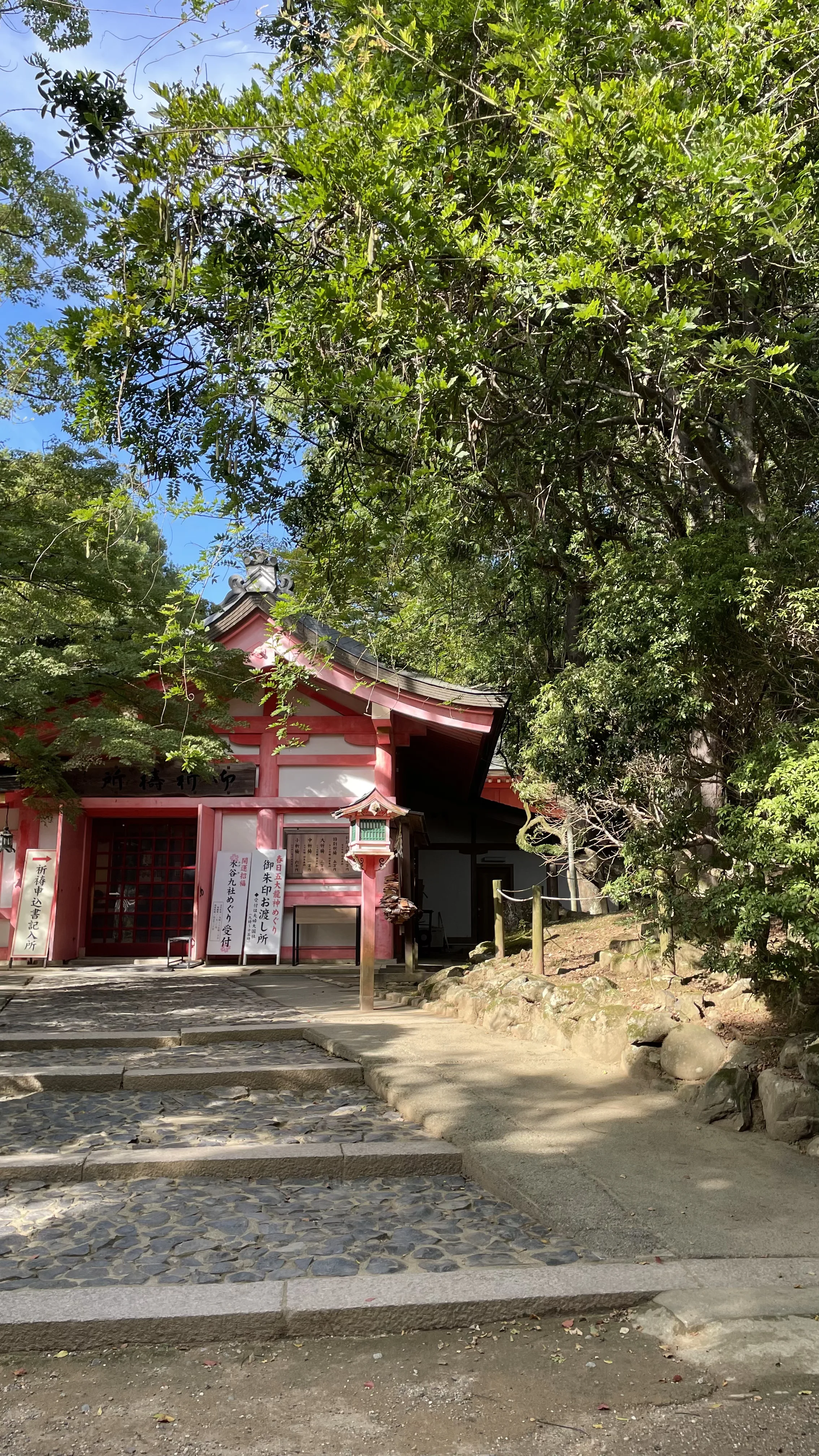 Caminho de pedra leva ao pavilhão de orações Gokitosho do Santuário Kasuga Taisha entre árvores em Nara, destino no Japão.