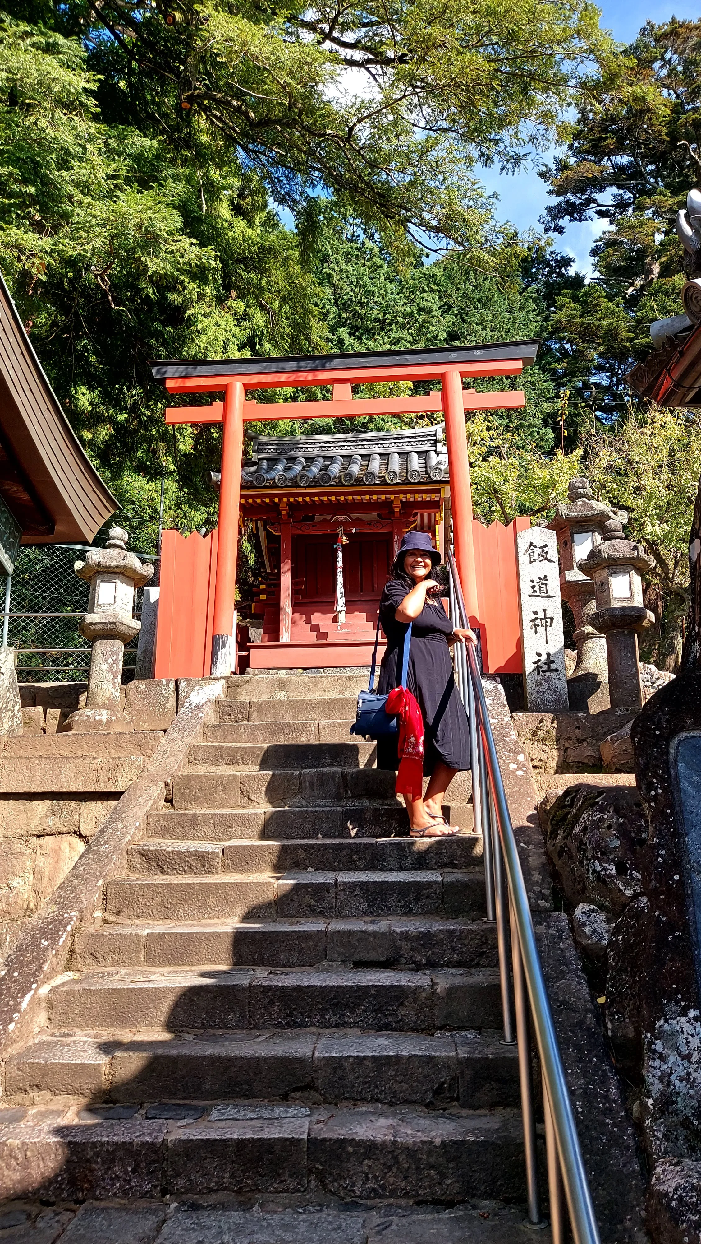 Turista sorri na escadaria do Santuário Iimichi Jinja com seu torii vermelho, atração histórica no Templo Todaiji em Nara, Japão.