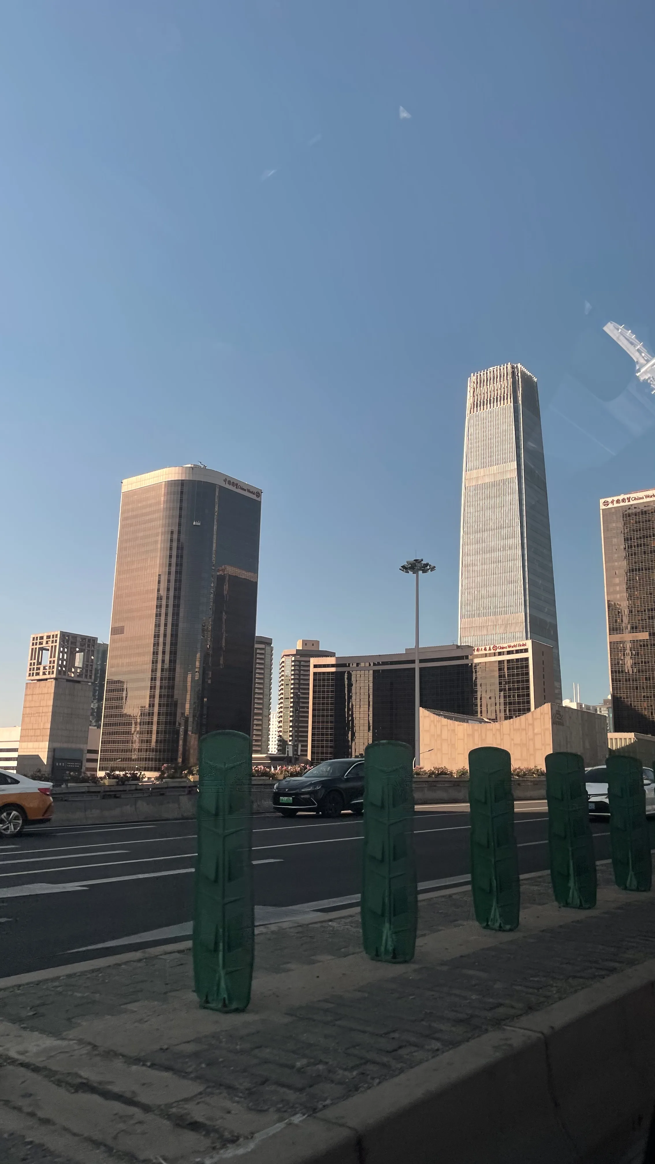 Arranha-céus modernos e torres comerciais sob o céu azul em avenida movimentada em Pequim.