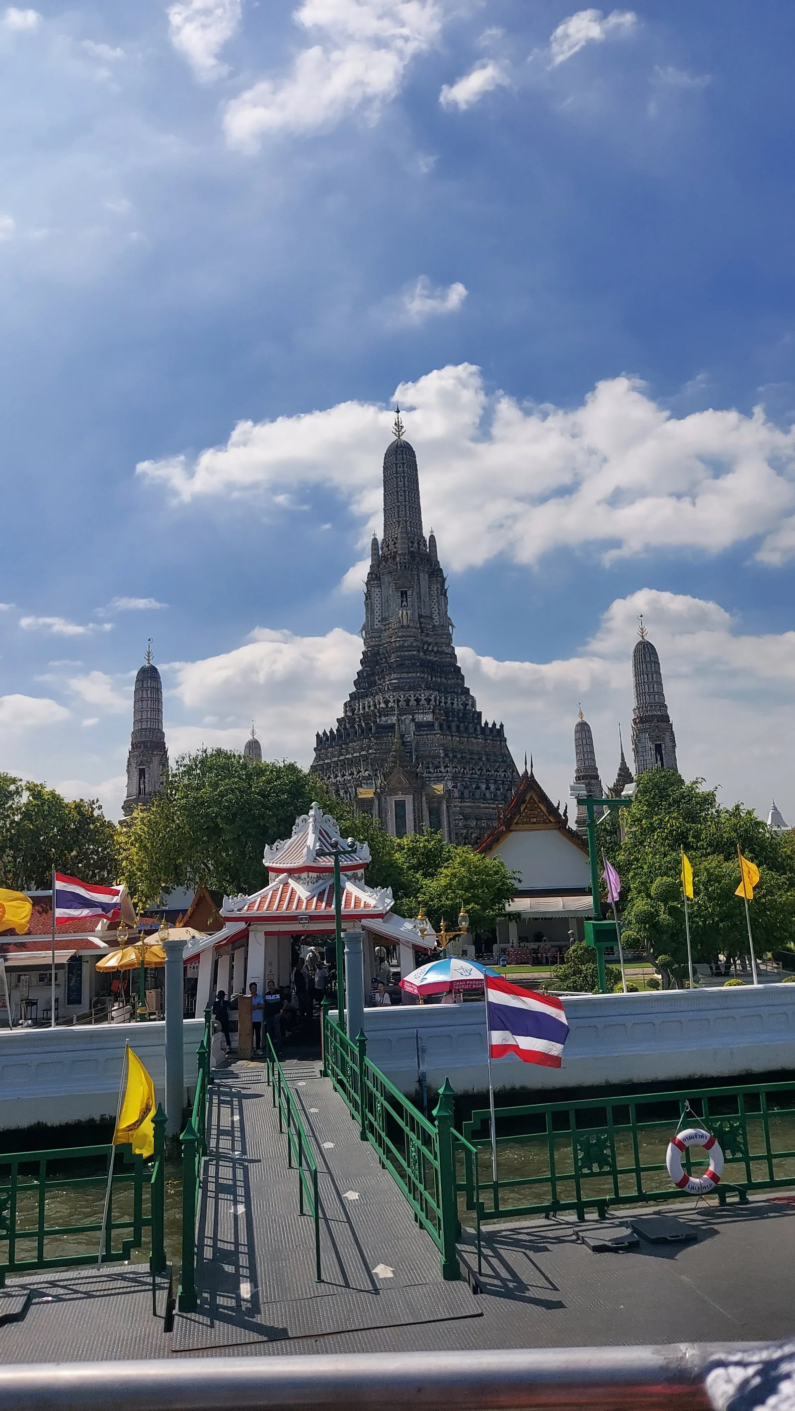 Torre principal prang do Wat Arun detalhada com porcelana colorida sob céu azul em Banguecoque.