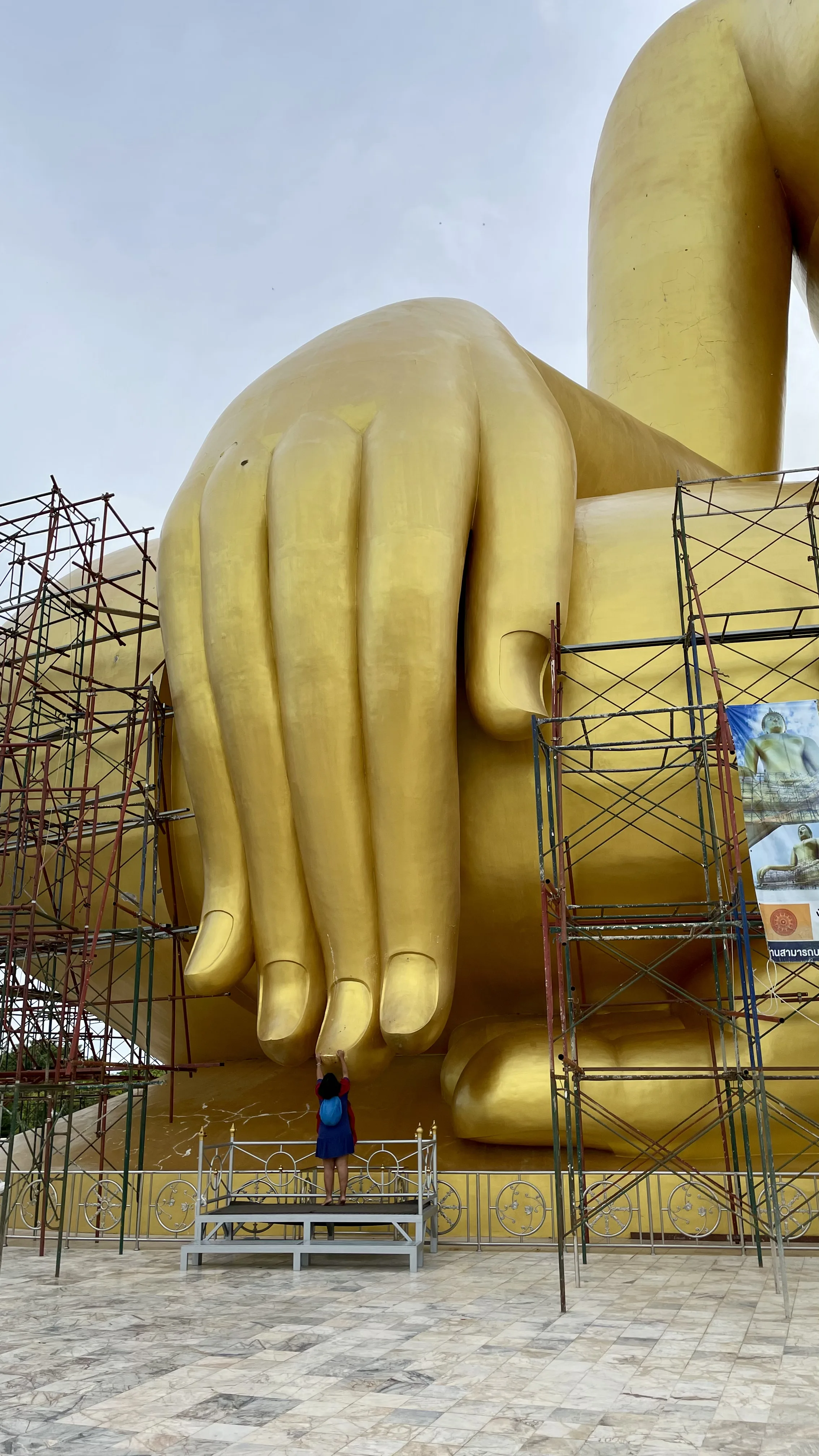 Visitante tocando a ponta do dedo gigante da mão do Grande Buda de Wat Muang
