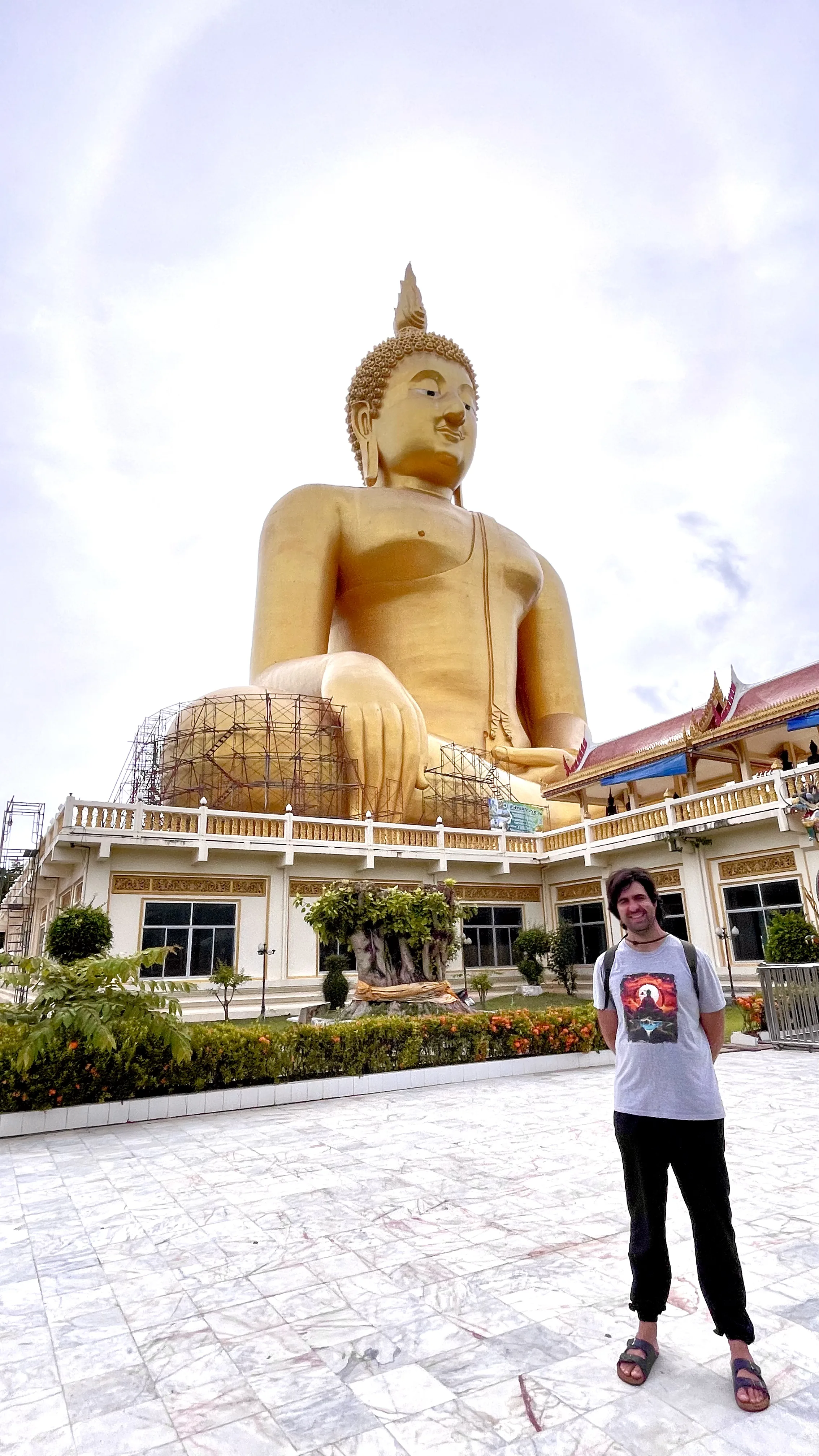 Visitante em pé diante da base monumental do Grande Buda de Wat Muang