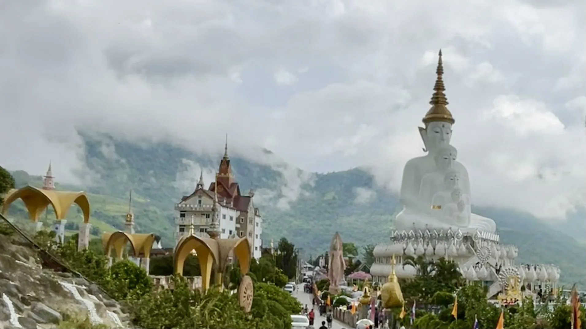 Vista panorâmica do complexo do templo Wat Phra That Pha Sorn Kaew, destacando a estátua dos cinco Budas e a arquitetura colorida entre montanhas nebulosas